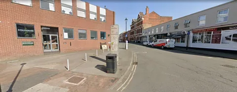 The DOLLHOUSE studio building on the corner of Warstone Lane and Spencer Street, Birmingham: red brick with glass front doors and DOLLHOUSE signs in the window